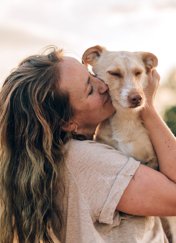 Owner Loving Dog woman holding and hugging her medium sized tan dog