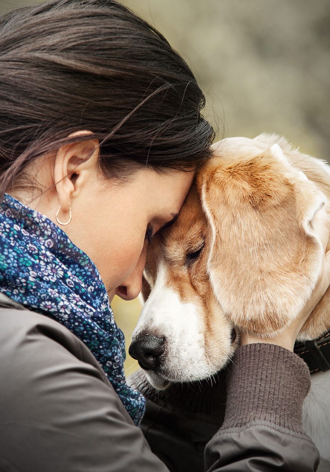 female lovingly pressing forehead to dog's head