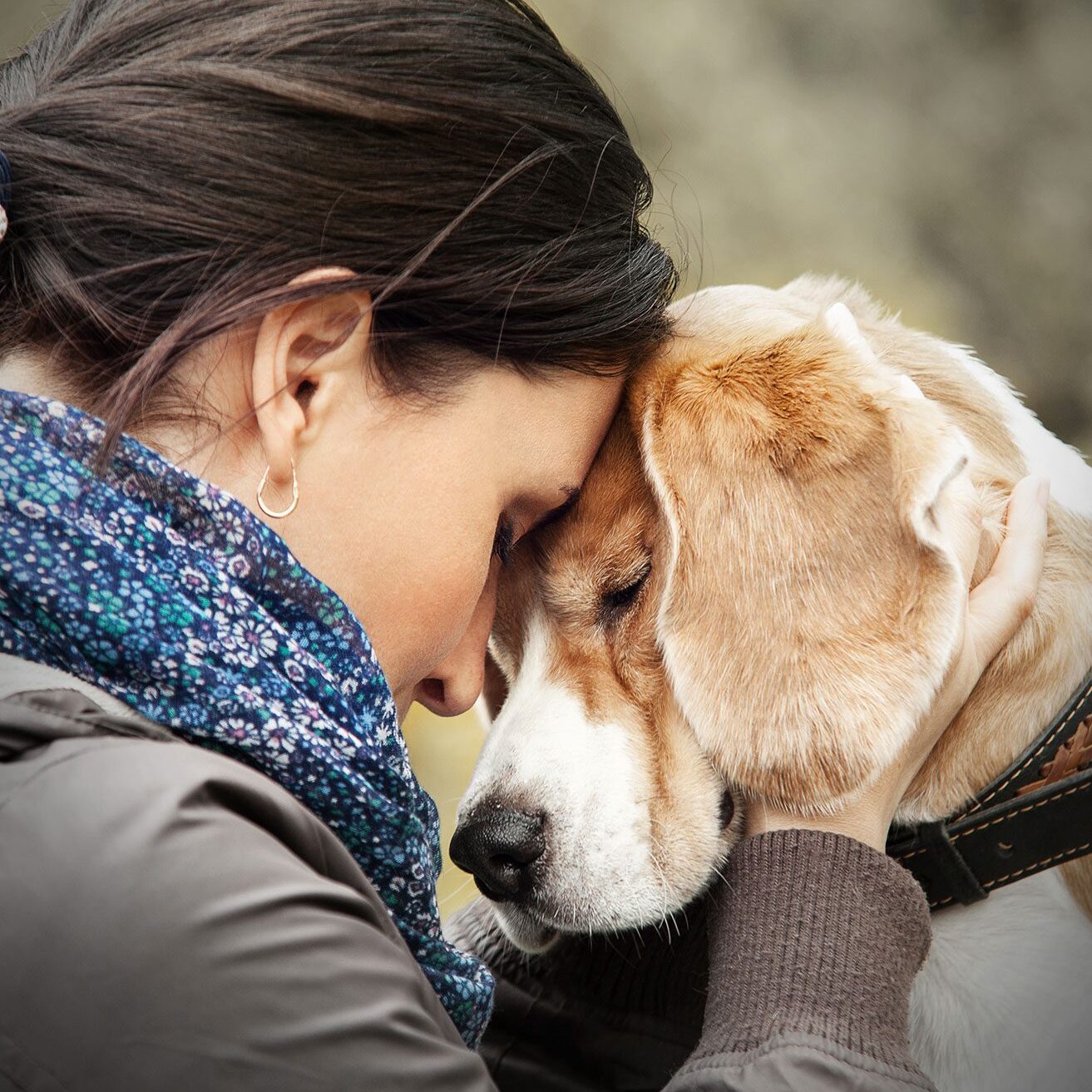 female lovingly pressing forehead to dog's head