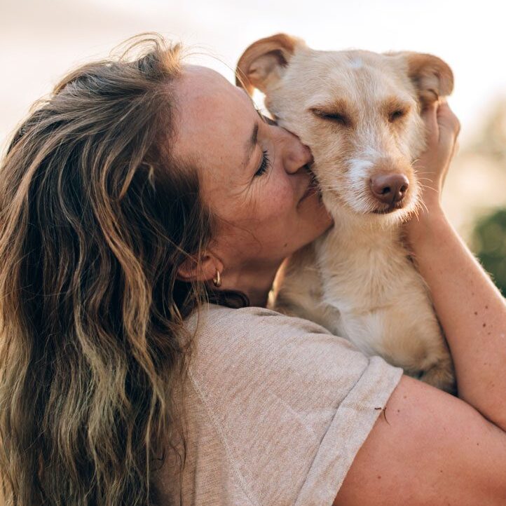 Owner Loving Dog woman holding and hugging her medium sized tan dog